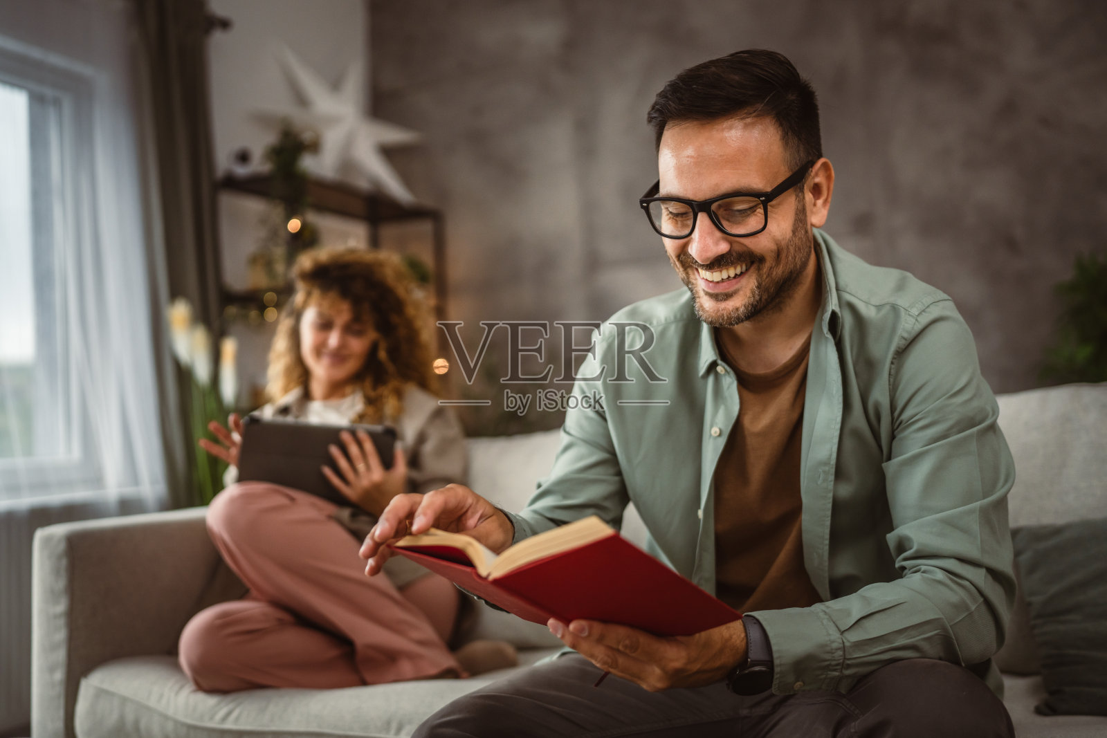 男朋友在看书,女朋友在家玩平板电脑照片摄影图片