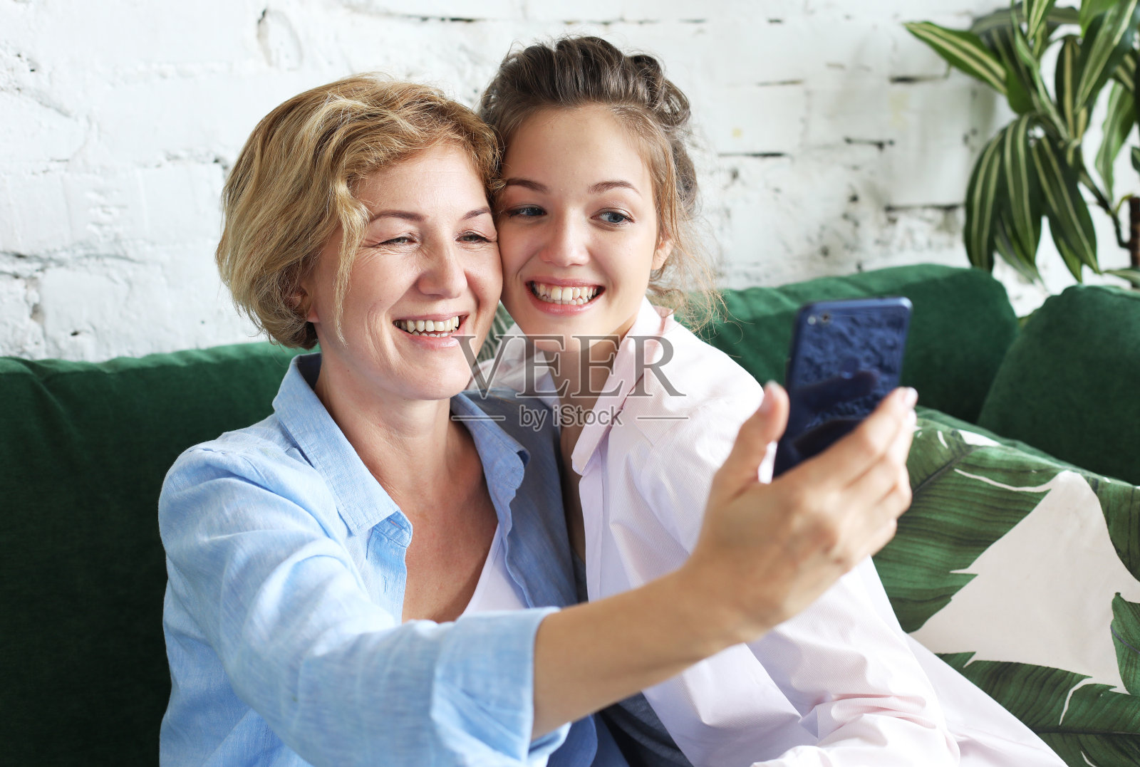 家庭,人和技术。一位老妇人和她已成年的女儿在家里使用智能手机。照片摄影图片