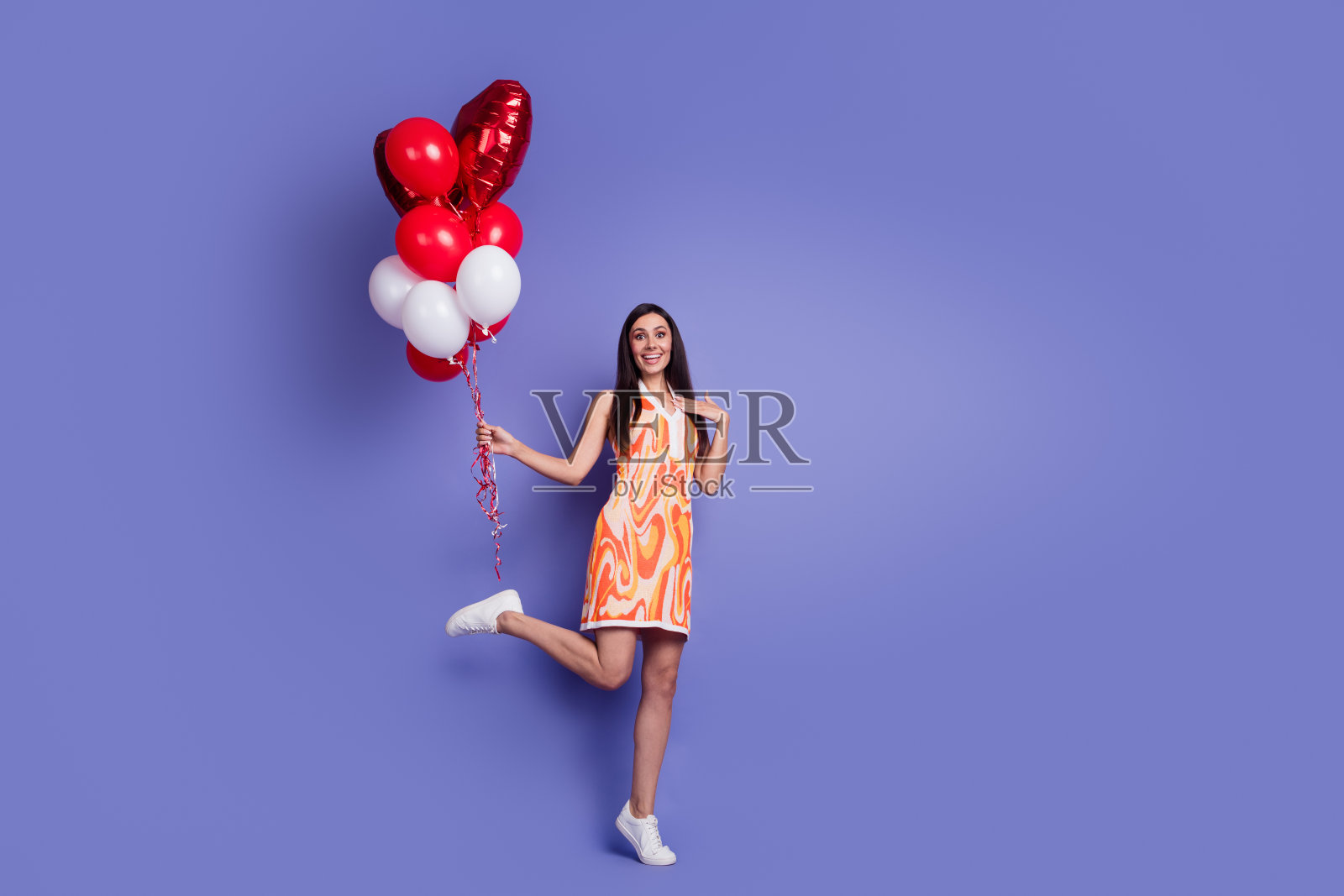 漂亮女士的全身画像,手持气球,空着空间,穿着紫色背景上孤立的衣服照片摄影图片