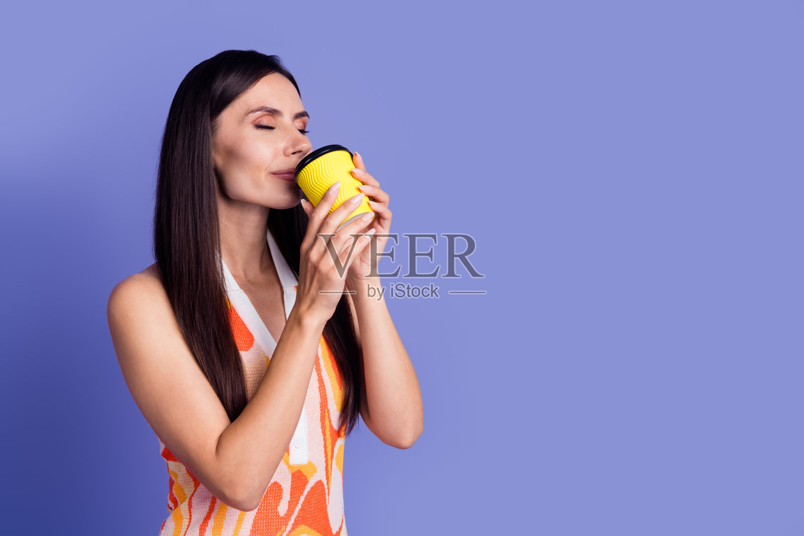 照片中甜美闪亮的女士穿着裙子,闭着眼睛享受着饮料,空旷的空间孤立的紫罗兰色背景照片摄影图片