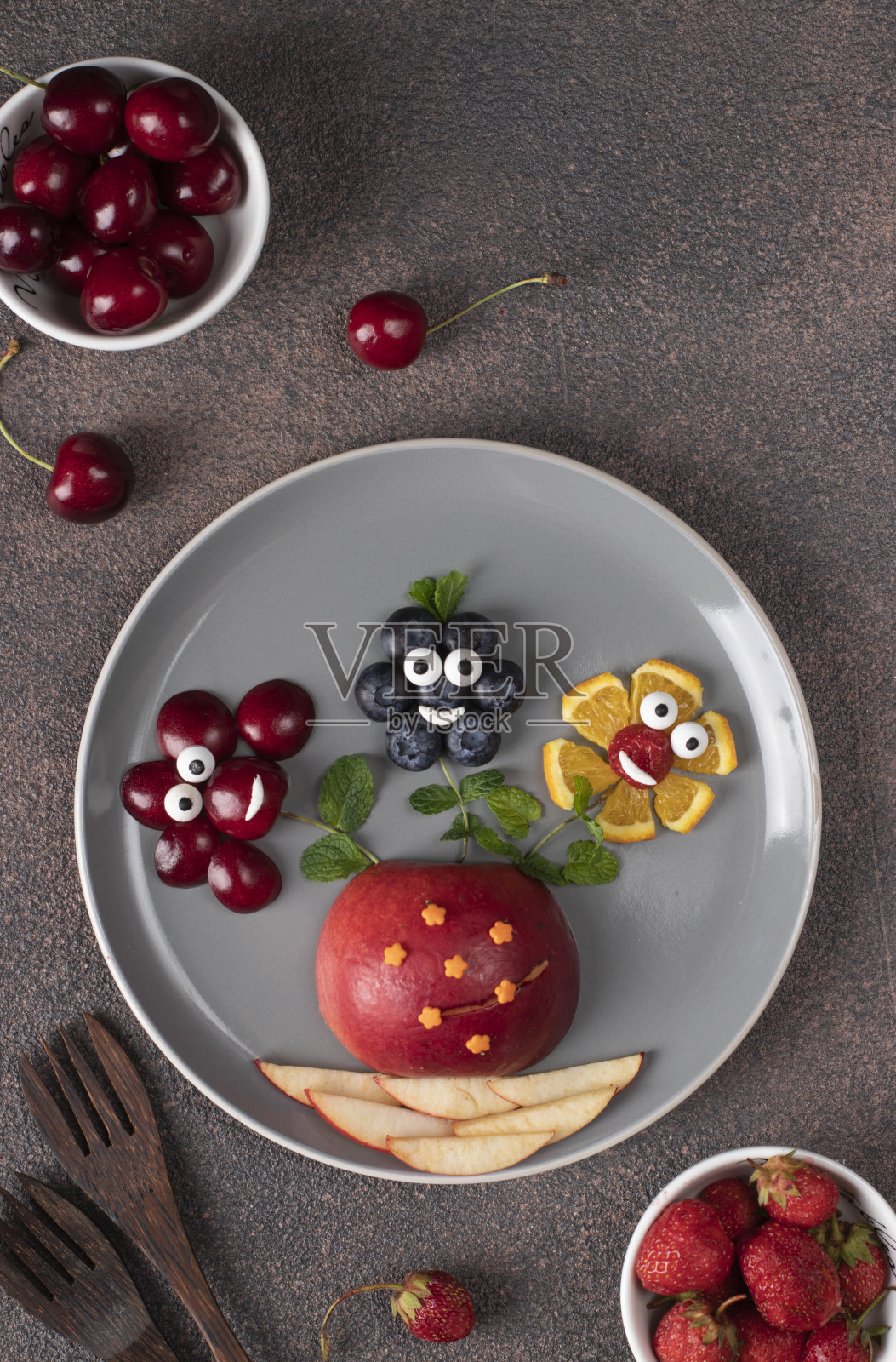 给孩子们的有趣的食物的想法-花瓶从浆果花放在灰色盘子在棕色的背景照片摄影图片