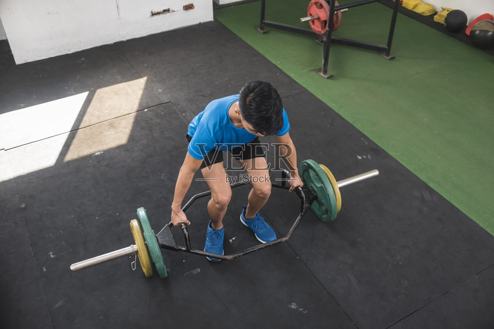 周末早上,一个专职的校队队员在健身房训练。举杠铃。为年轻运动员制定的严格的锻炼计划。照片摄影图片