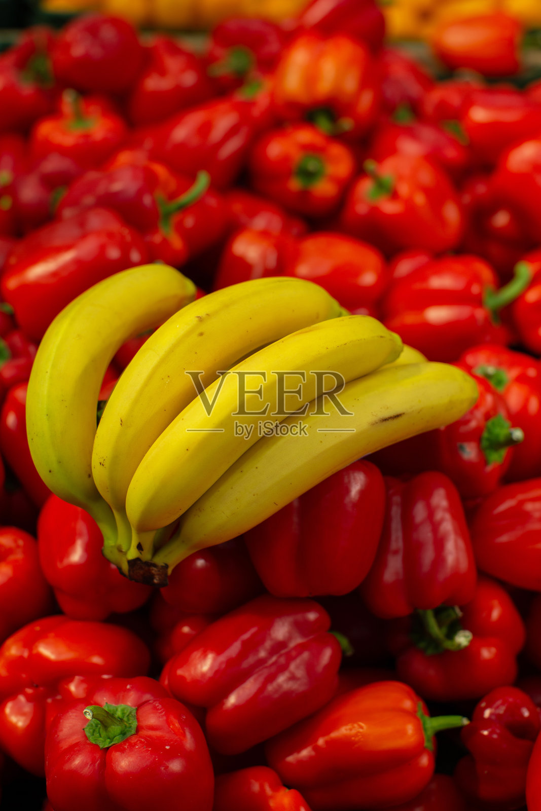 商店橱窗上挂着一串成熟的香蕉和辣椒。照片摄影图片