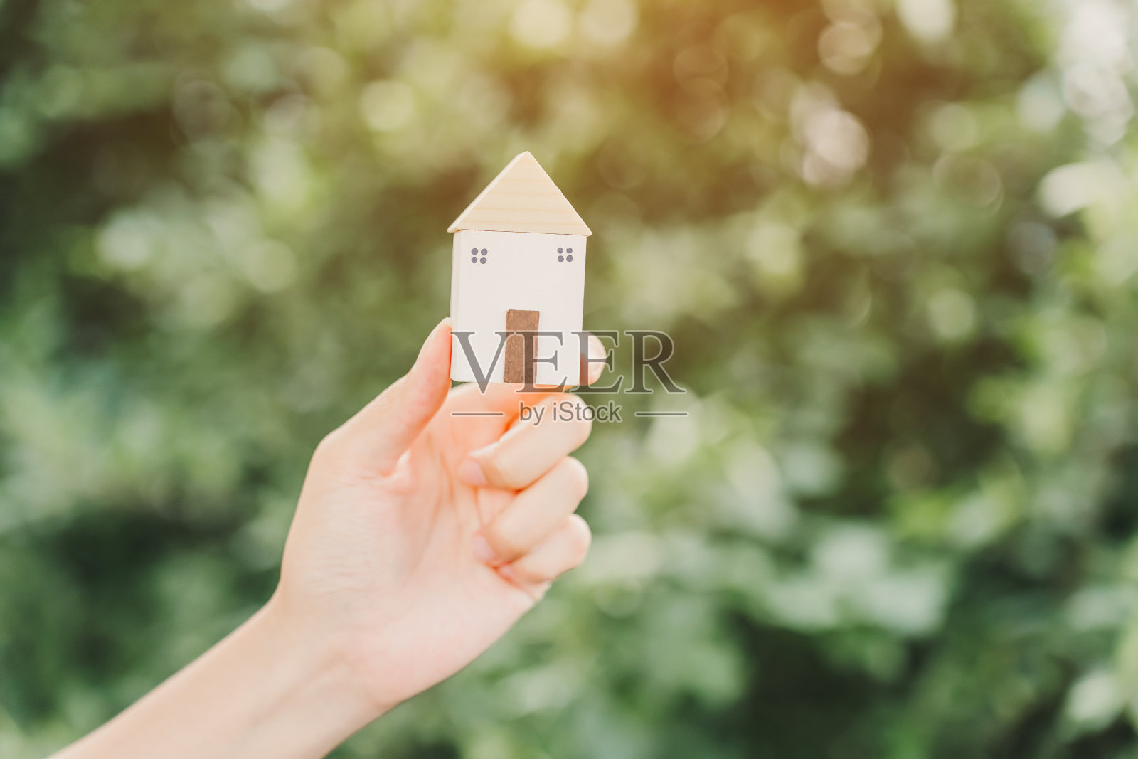 一个女人的手握着一个小木屋。照片摄影图片