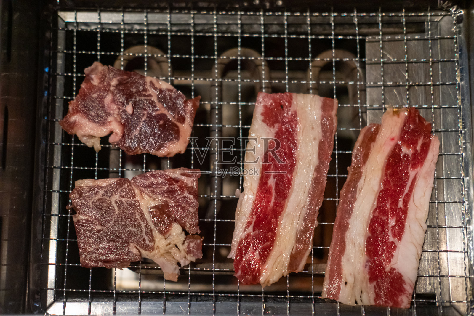 不锈钢烤架上的韩式烧烤。烧烤半熟的肉与软焦点照片摄影图片