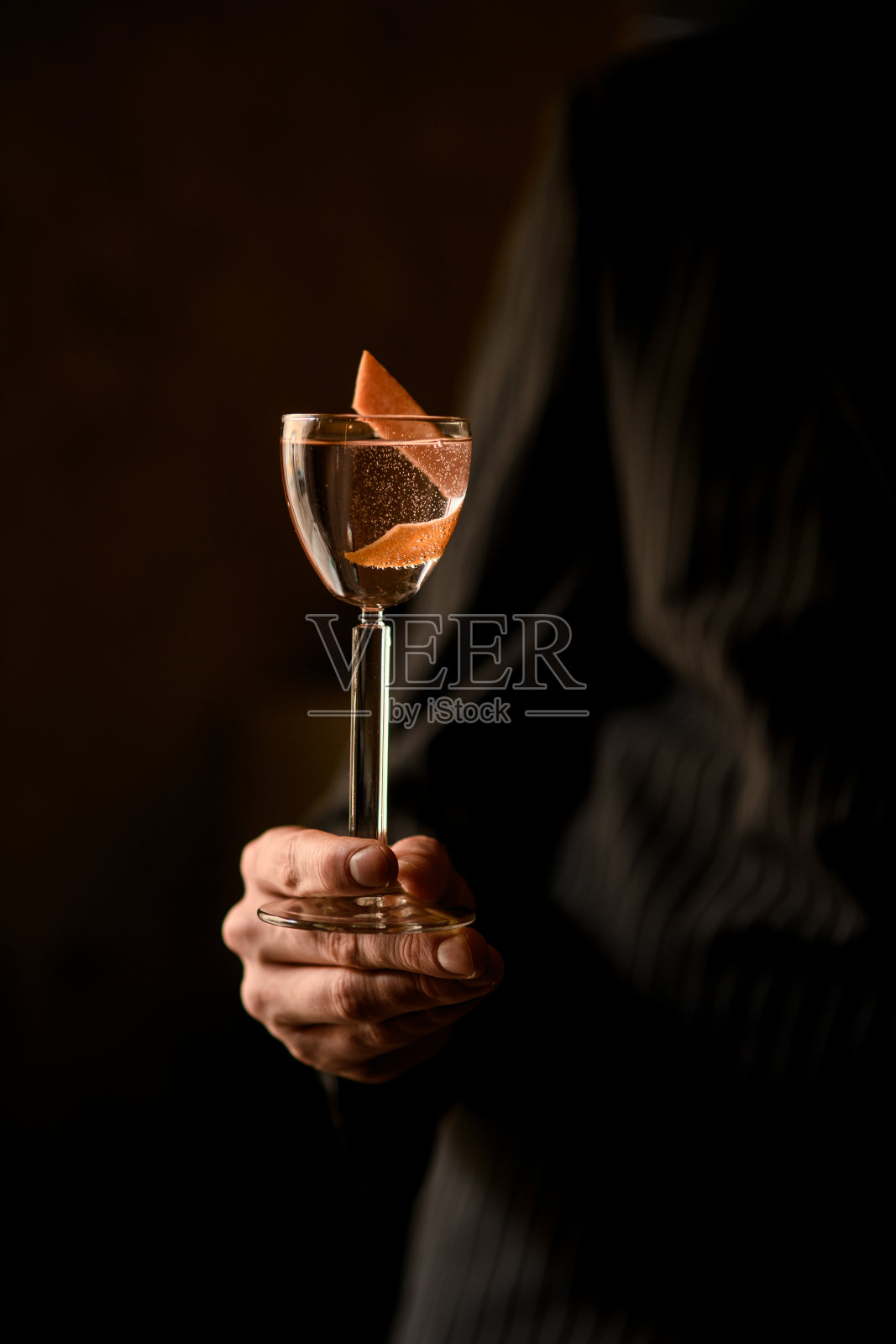 男调酒师手里拿着一个装有伏特加酒皮的玻璃杯照片摄影图片