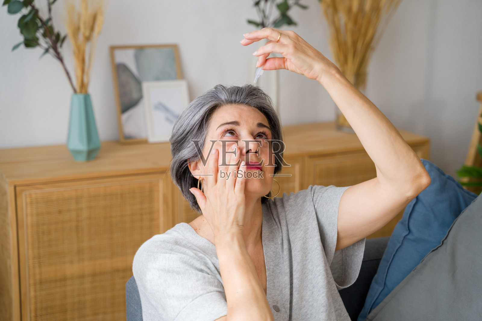 患有白内障的老年妇女正在使用眼药水照片摄影图片