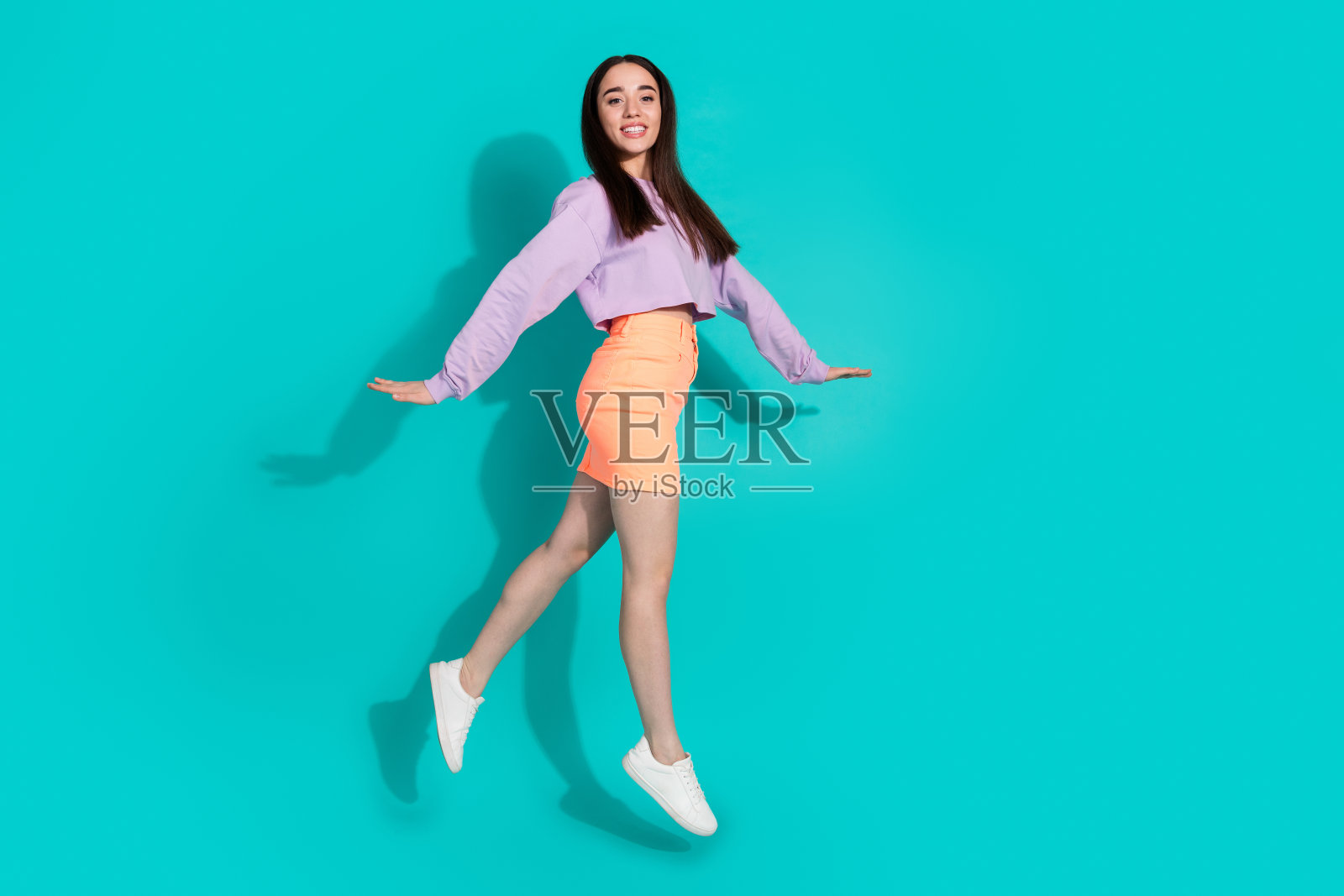 可爱可爱的女孩穿着短裙跳高走空空间孤立的绿松石色背景照片摄影图片