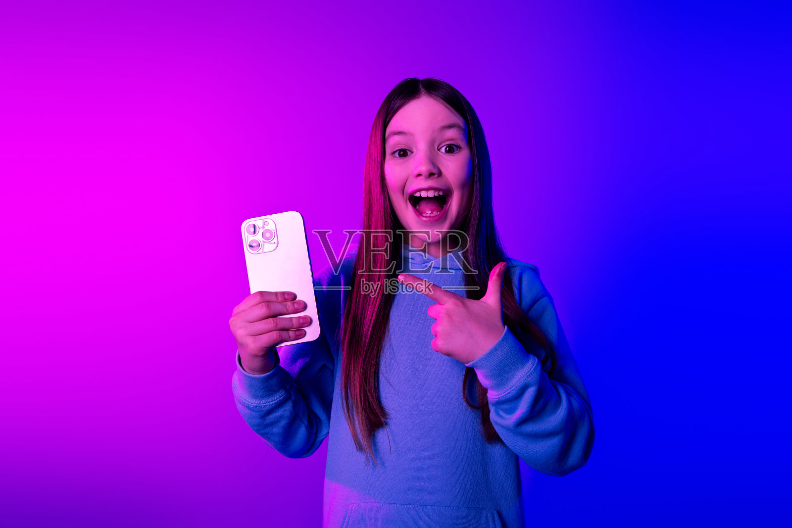 照片的闪亮兴奋的小女士穿着连帽衫显示现代小工具空空间孤立的霓虹粉色背景照片摄影图片