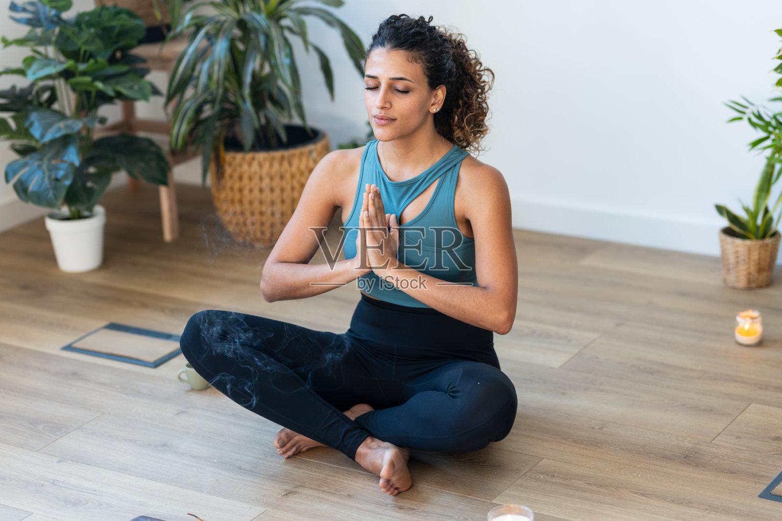 运动的年轻女子在家里的客厅里保持莲花姿势,做瑜伽和低血压运动。照片摄影图片