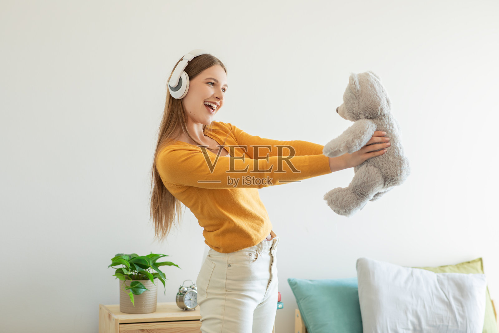 女孩抱着泰迪熊,听着耳机照片摄影图片