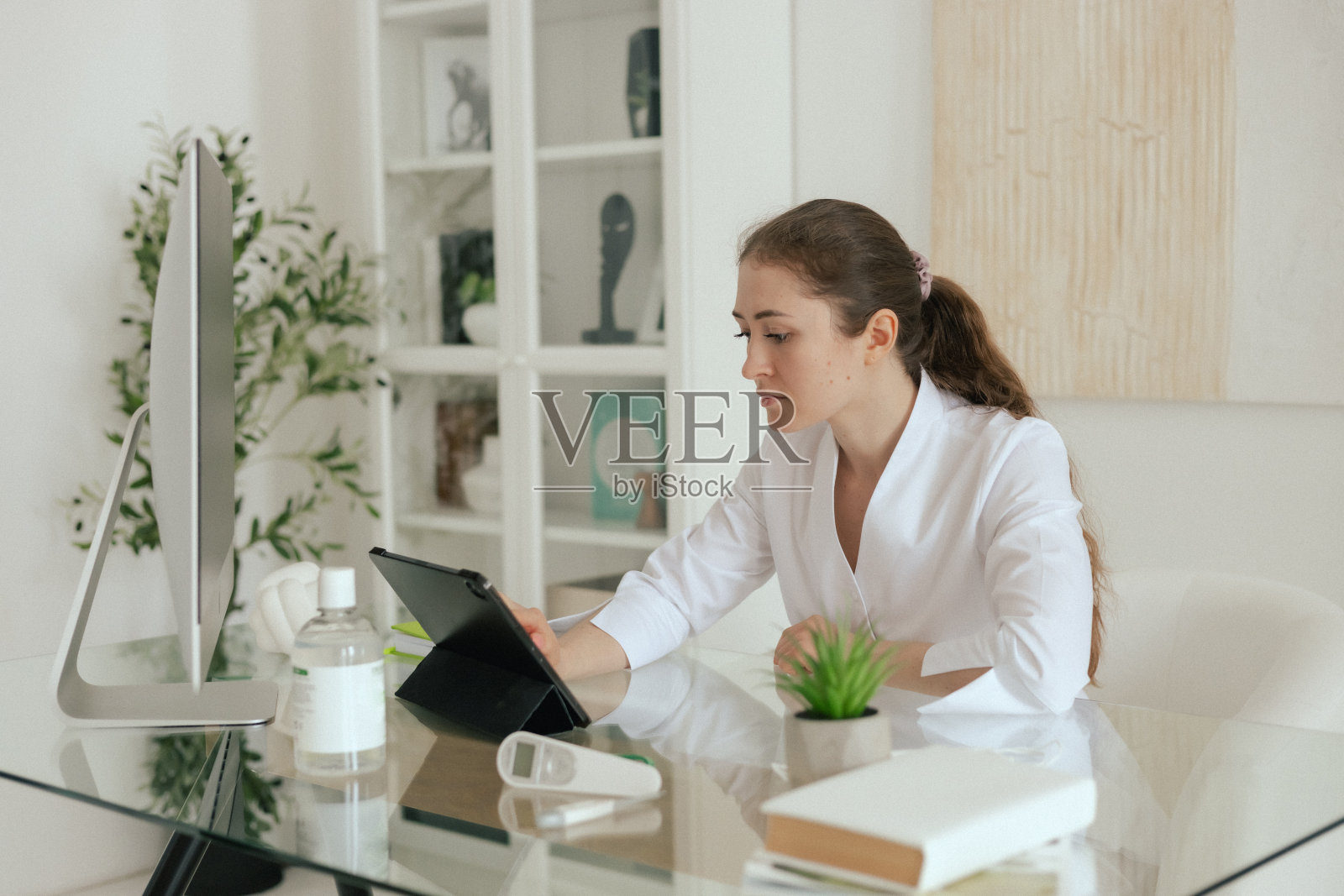 医学、医疗保健和技术理念——友好的女全科医生,穿着白色服装的医生,使用数字平板电脑上的软件应用程序,在诊所办公室分析病史照片摄影图片