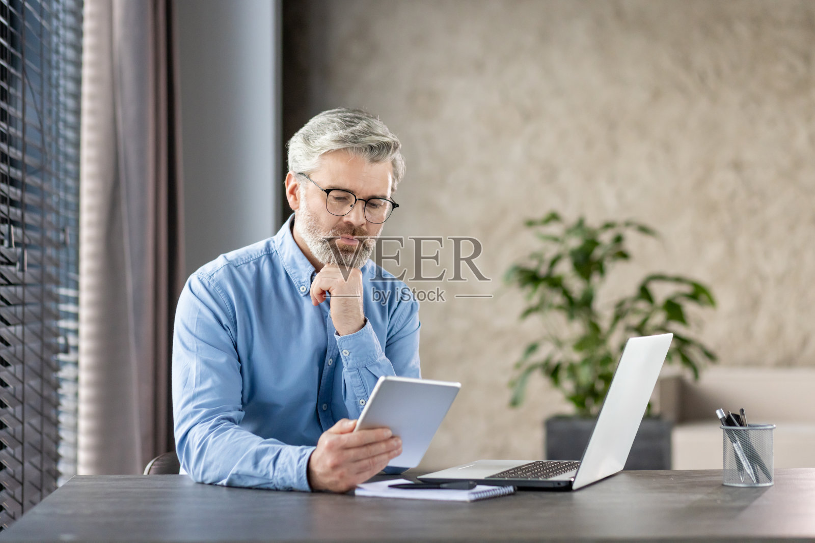 高级商人在家庭办公桌上用平板电脑工作照片摄影图片