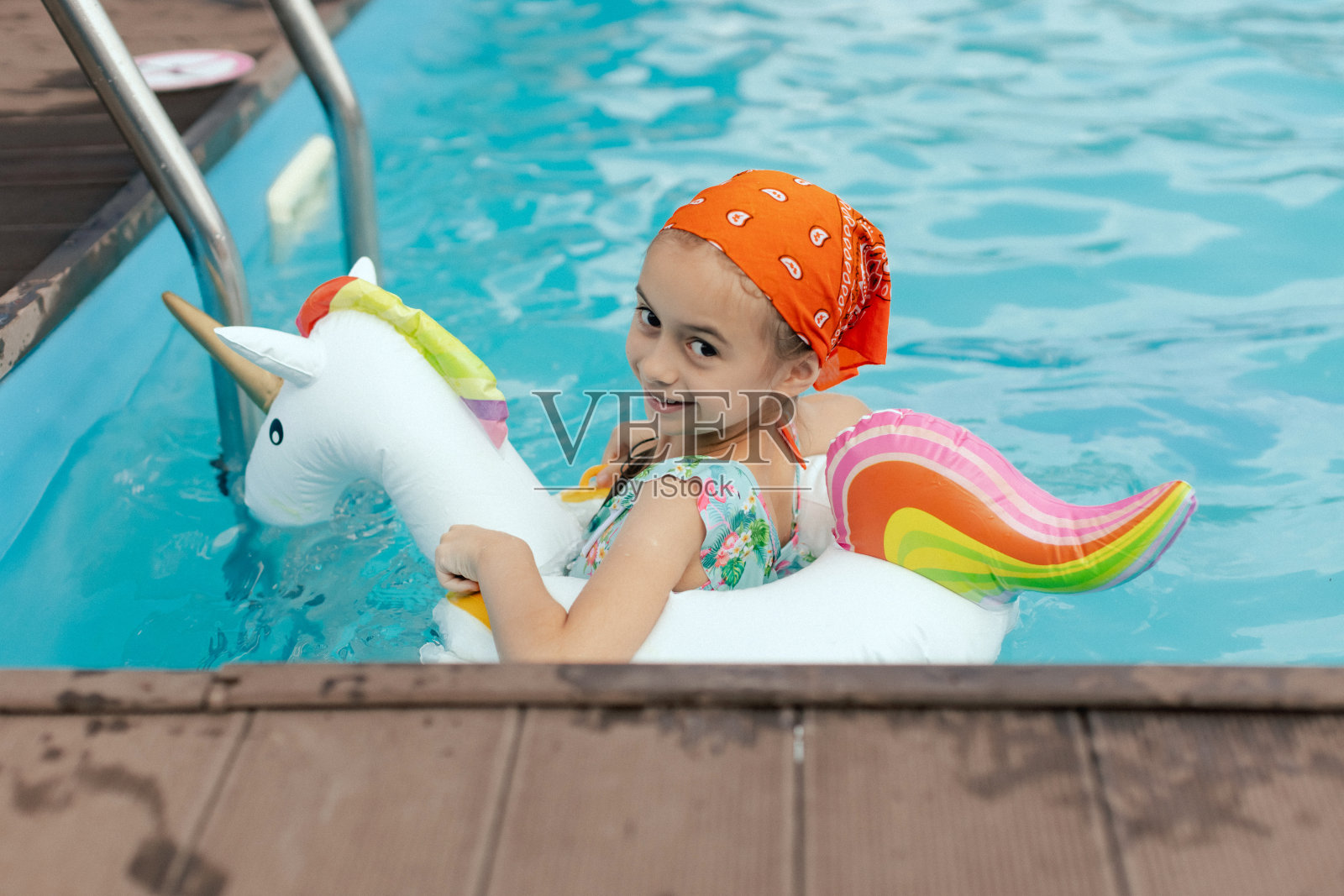 小女孩与充气独角兽游泳的特写肖像。快乐的孩子在水里玩耍,海滩度假,暑假和假期的概念。女孩展示了一个快乐的夏日氛围。照片摄影图片