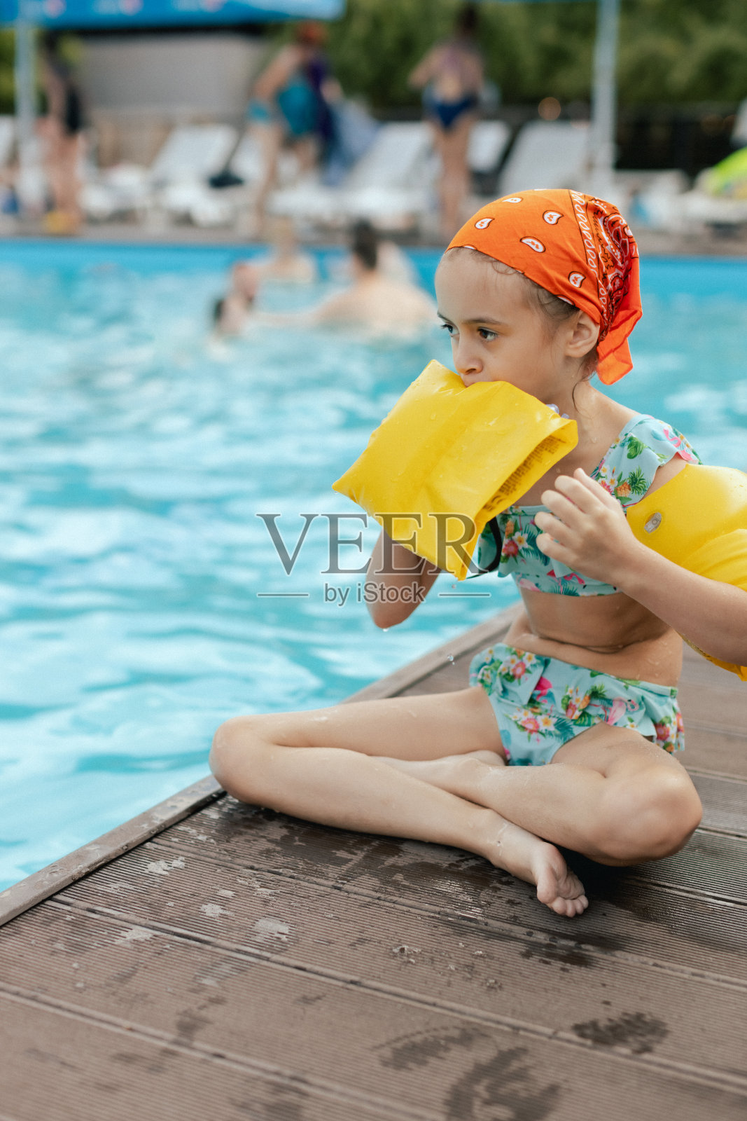 小女孩在游泳池里膨胀着她的游泳袖的特写肖像。快乐的孩子在水里玩耍,海滩度假,暑假和假期的概念。女孩展示了一个快乐的夏日氛围照片摄影图片