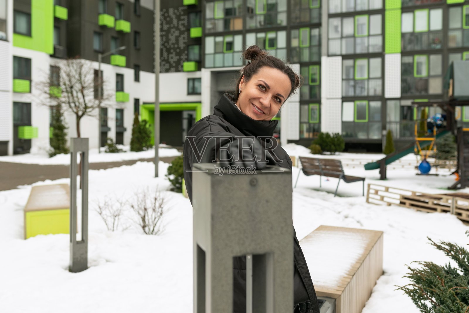 生活方式的概念,无忧无虑的黑发女人穿着黑色冬季夹克与发髻在街上照片摄影图片