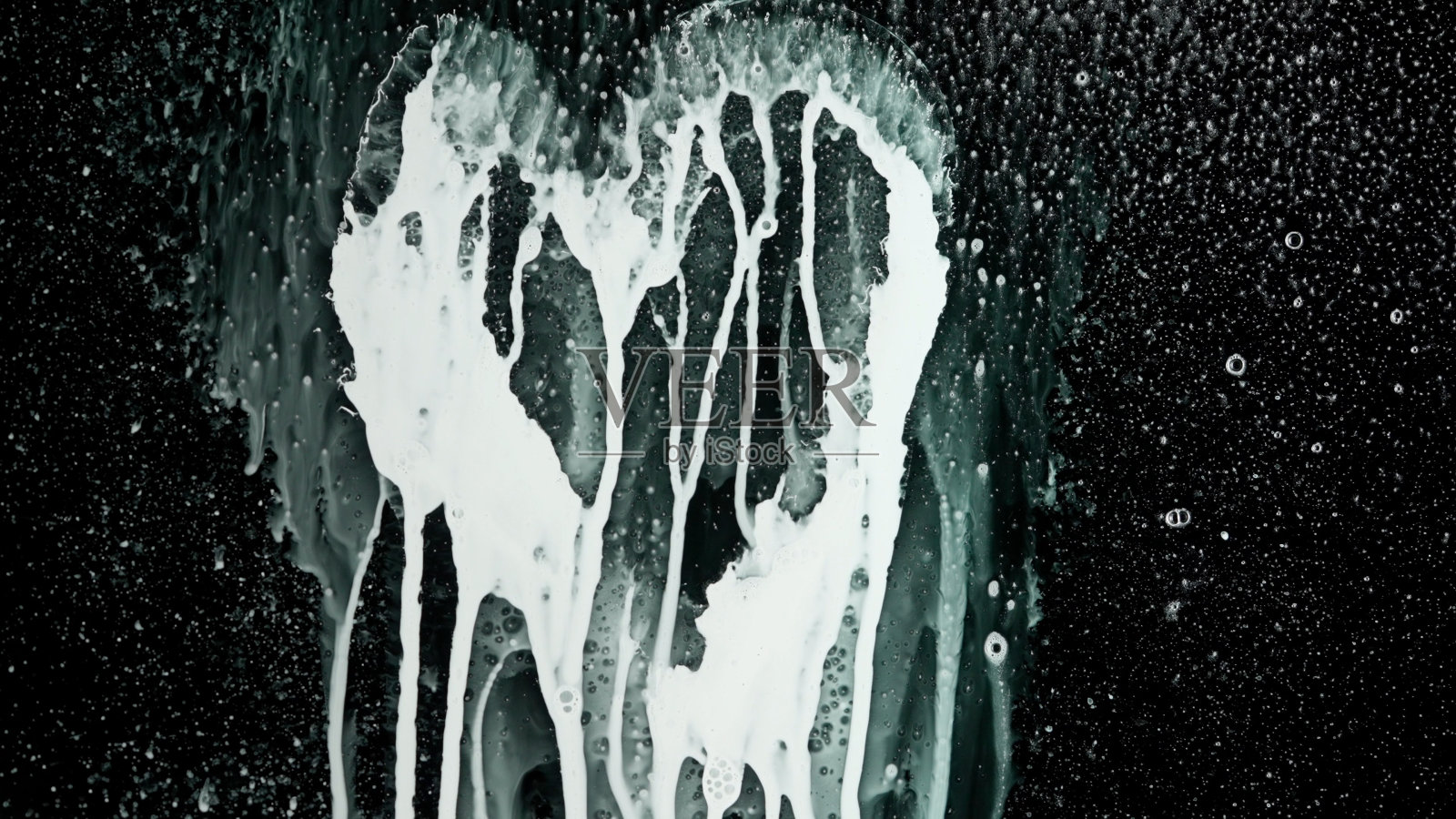 人在黑色的玻璃屏幕上喷泡沫,孤立的背景用丙烯酸油彩画出心脏标志,液体流下,对面的景色。照片摄影图片