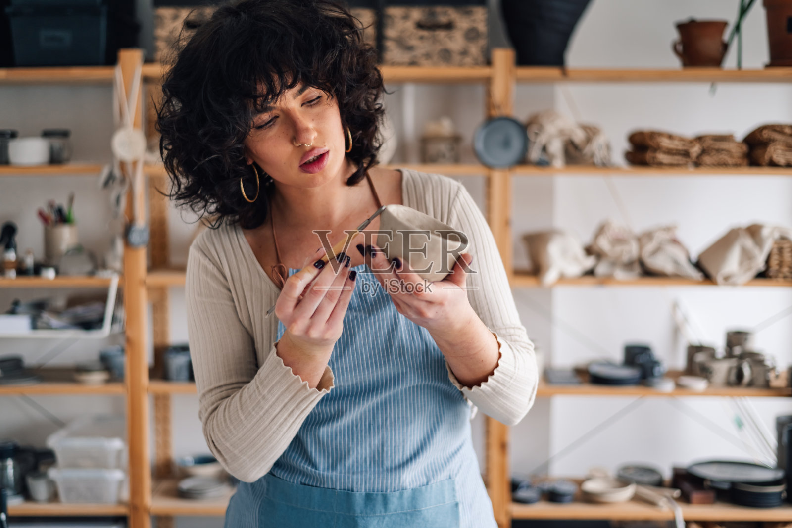 陶工女工在陶艺车间装饰陶土的肖像。照片摄影图片