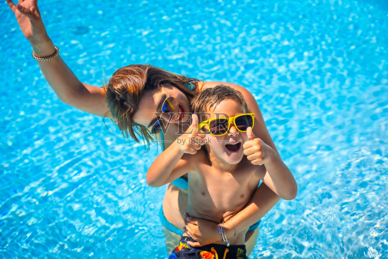 男孩和他妈妈在游泳池里玩得很开心照片摄影图片