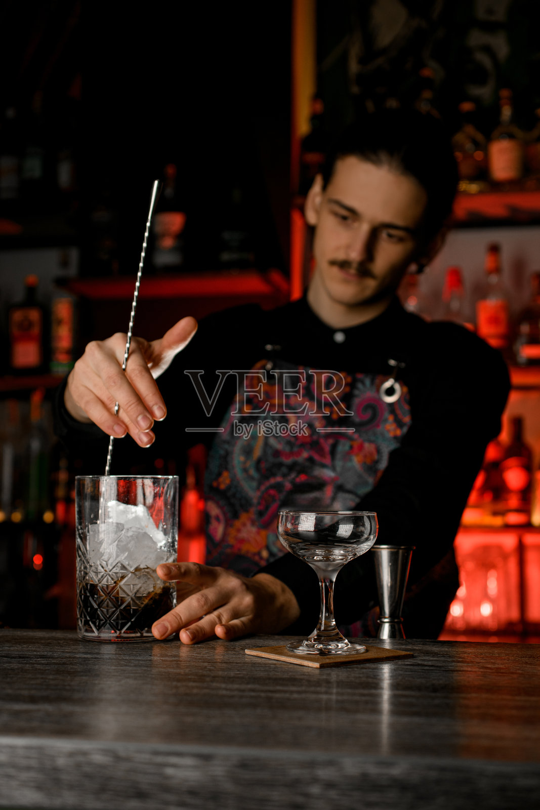 留胡子的帅哥在玻璃杯里加冰混合酒精鸡尾酒照片摄影图片