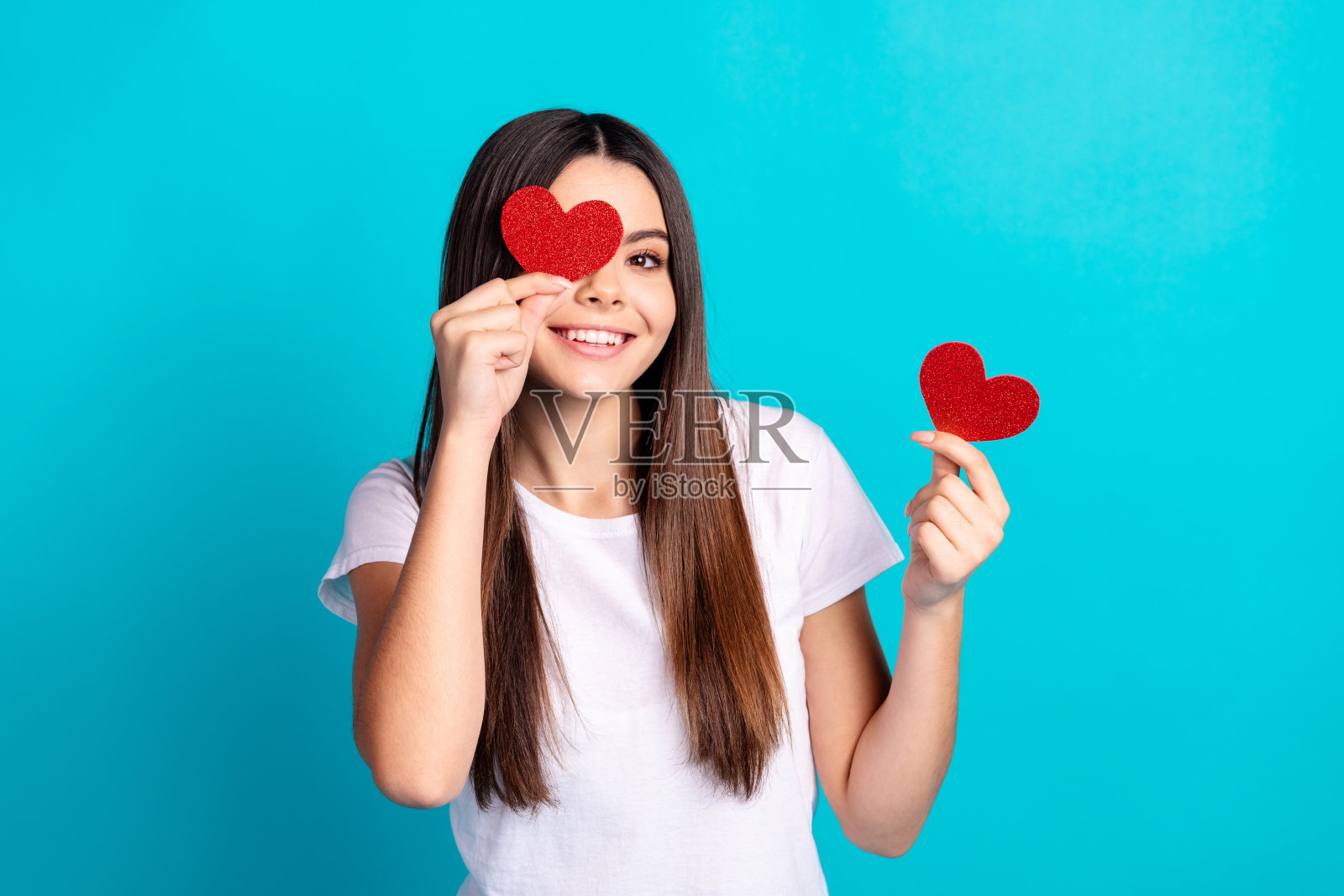 漂亮女孩的肖像拿着小心脏,穿着绿松石色背景上孤立的t恤照片摄影图片