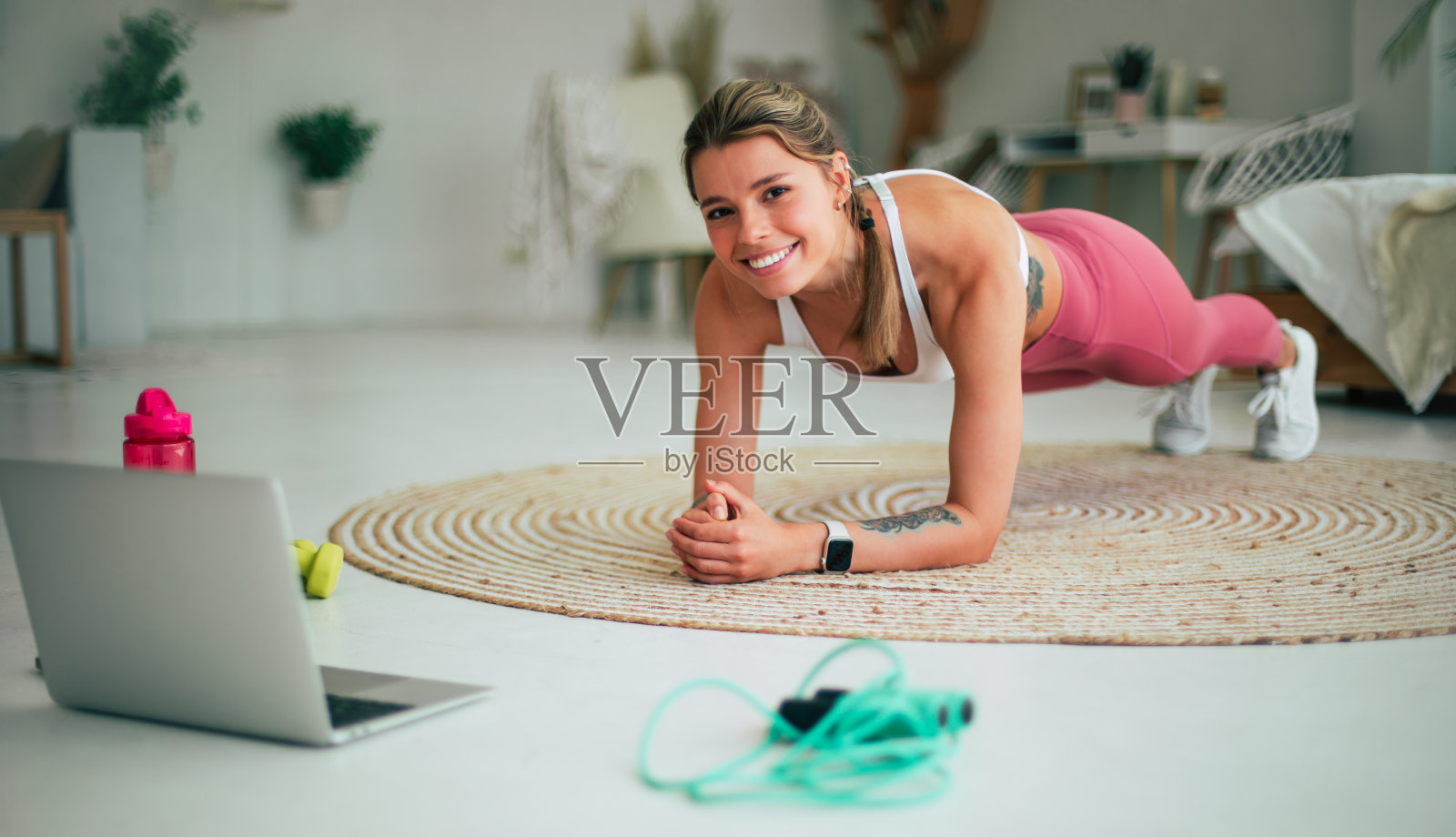 微笑的运动女性博主穿着运动服,在笔记本电脑上拍摄在线视频课程,在家做伸展运动。居家运动休闲理念。培训师,教练,指导员,教学照片摄影图片