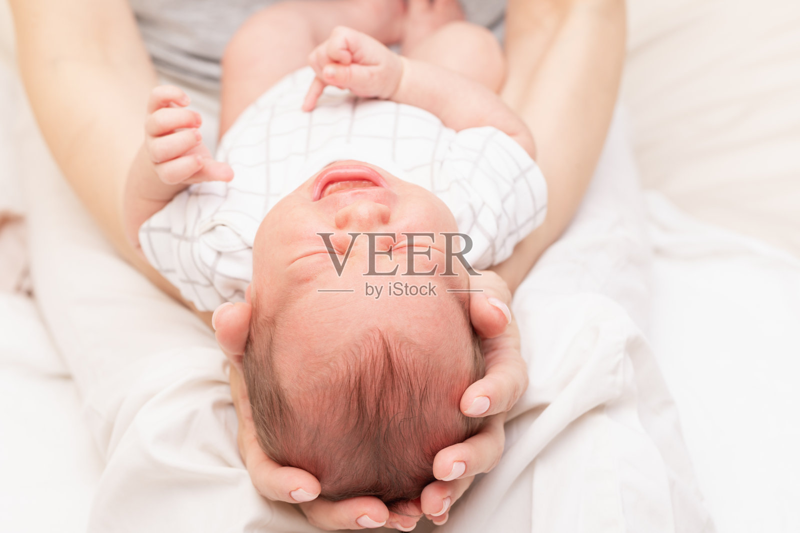 母亲把哭泣的新生儿抱在怀里照片摄影图片