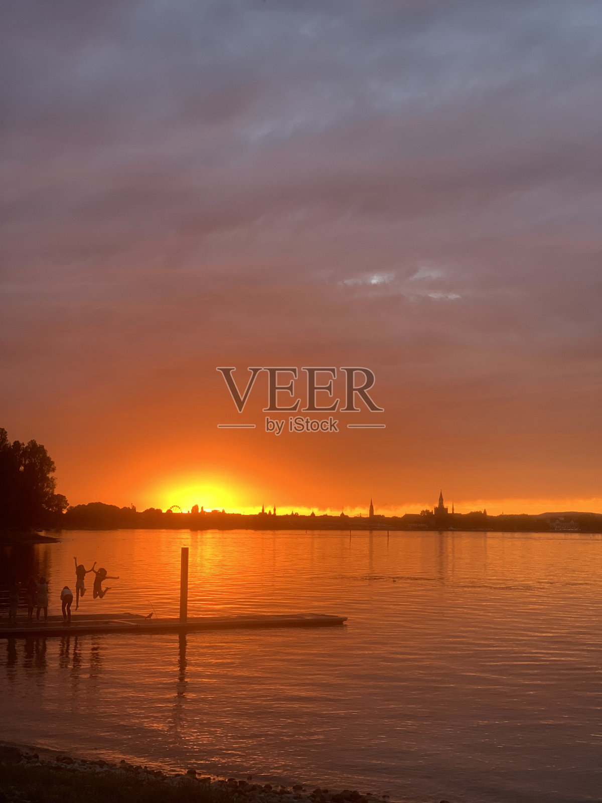 夕阳下的康斯坦斯湖,人们跳入水中照片摄影图片