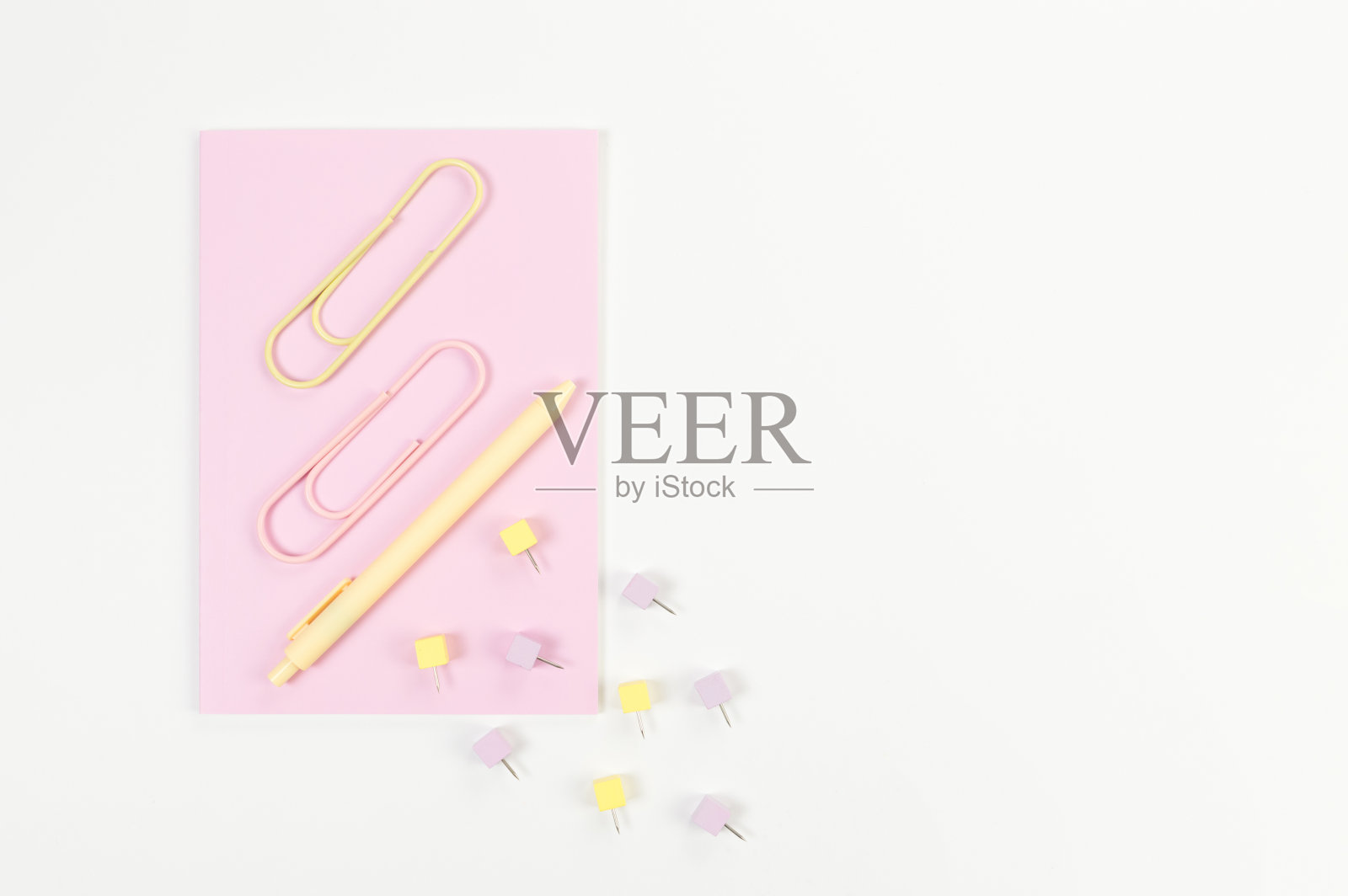 白色背景上粉红色笔记本的顶视图。回形针、笔和别针。学校、办公室的墙纸。照片摄影图片