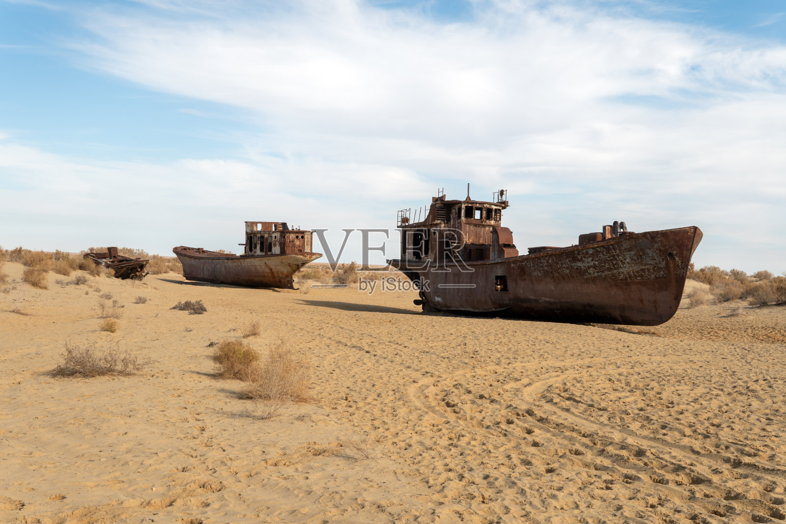 沉船。咸海生态灾害。在乌兹别克斯坦咸海港口城市莫伊纳克的船舶墓地,生锈的船只。一艘废弃的旧船停在日渐干涸的咸海岸边。照片摄影图片