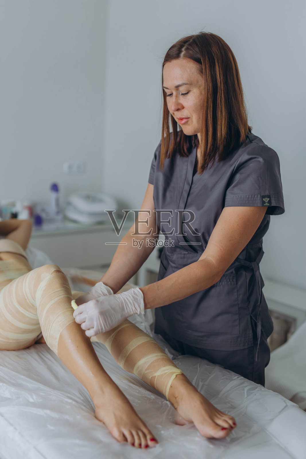 在美容院,专业的美容师在完成包裹程序后将所有的绷带拆除。照片摄影图片