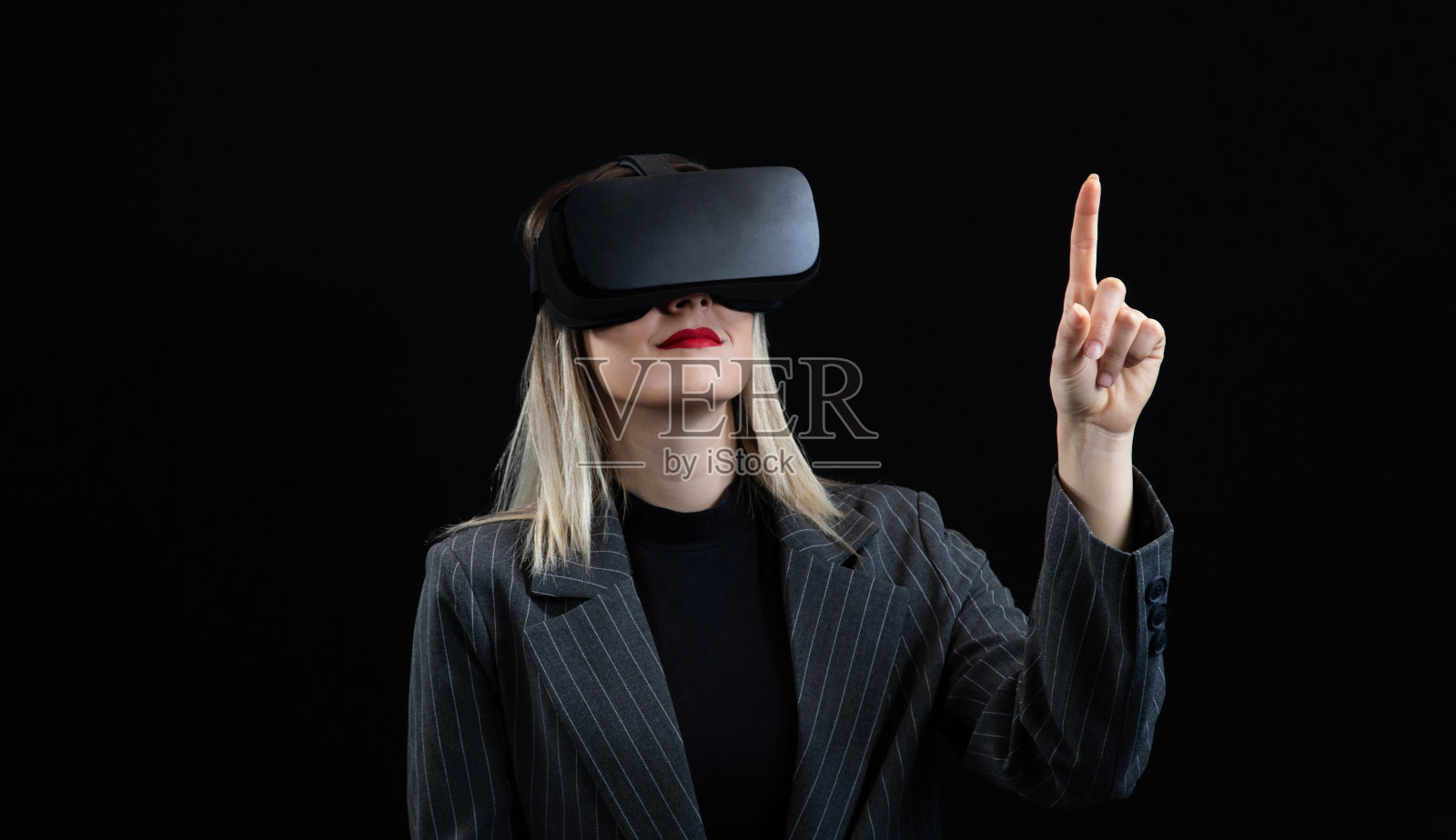 戴着虚拟现实眼镜的女性,在黑色背景下用虚拟现实耳机观看360度视频。触摸屏幕的女人照片摄影图片