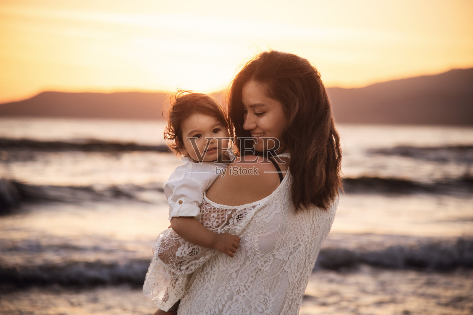 母亲和孩子在海滩上欣赏日落照片摄影图片