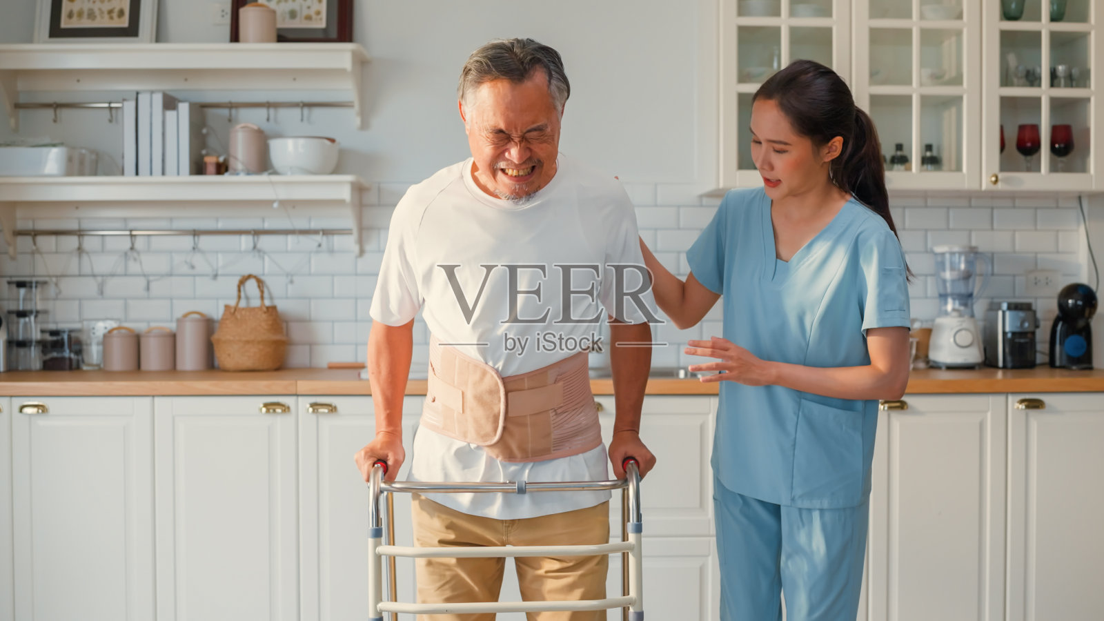 亚洲护工护士物理治疗师指导鼓励病人老年人使用助行器在家中客厅行走,专业护士物理治疗和保健与运动康复,医疗和保险照片摄影图片