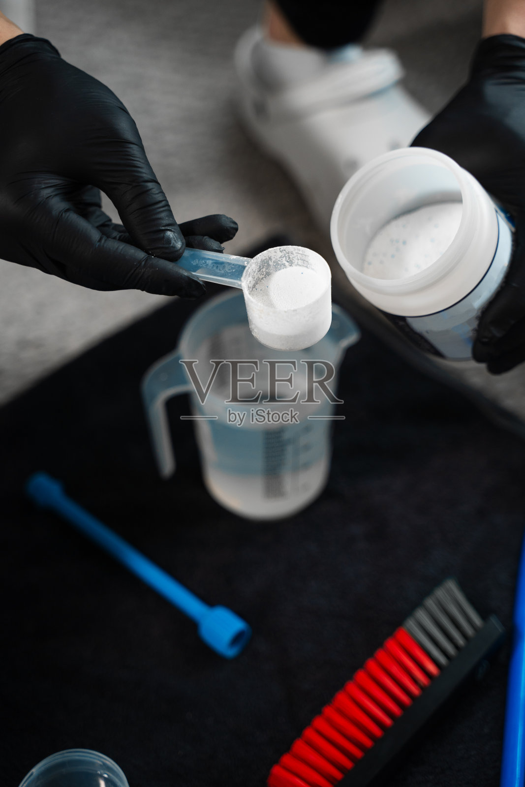 测定清洁家具用氧漂白剂与水的比例。将干洗粉倒入水中。清洗剂和漂白剂有效清洗。照片摄影图片