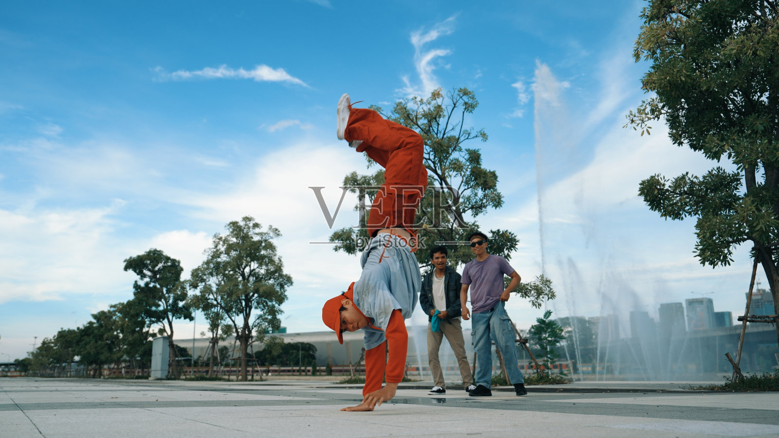 亚洲熟练的潮人在喷泉附近的相机前做定格姿势。活泼的。照片摄影图片