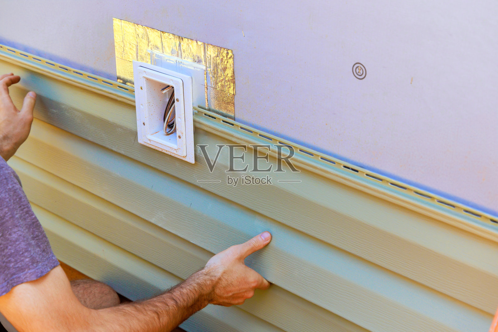 一名员工在新建筑的外墙安装了乙烯基塑料护墙板照片摄影图片