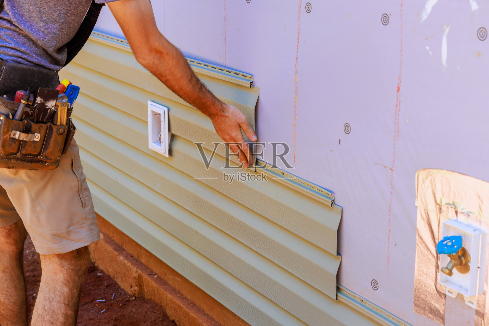 一名员工在新住宅的外墙安装乙烯基塑料护墙板照片摄影图片