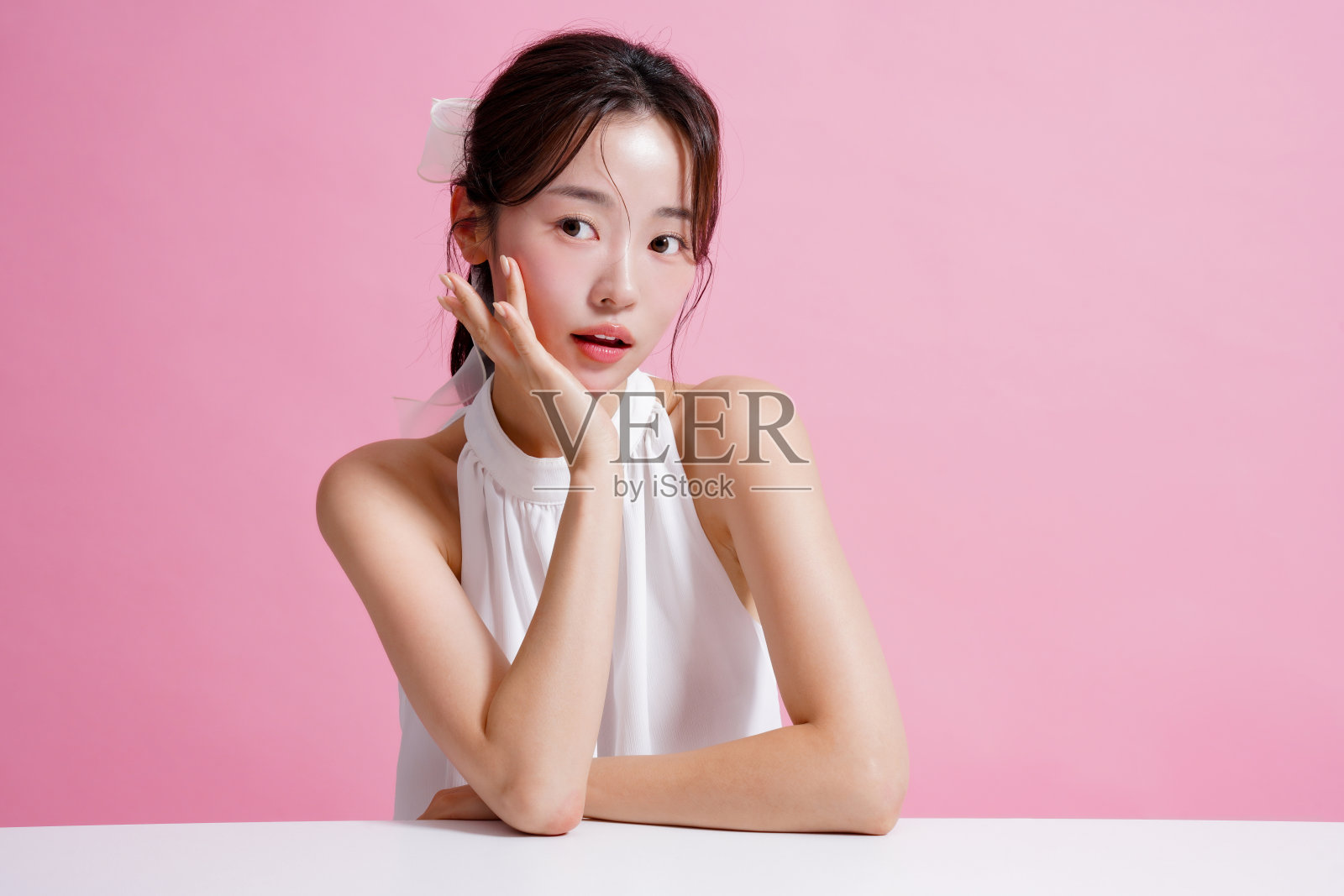 一个年轻的亚洲女性在粉红色背景下拍摄的浅色肖像照片摄影图片