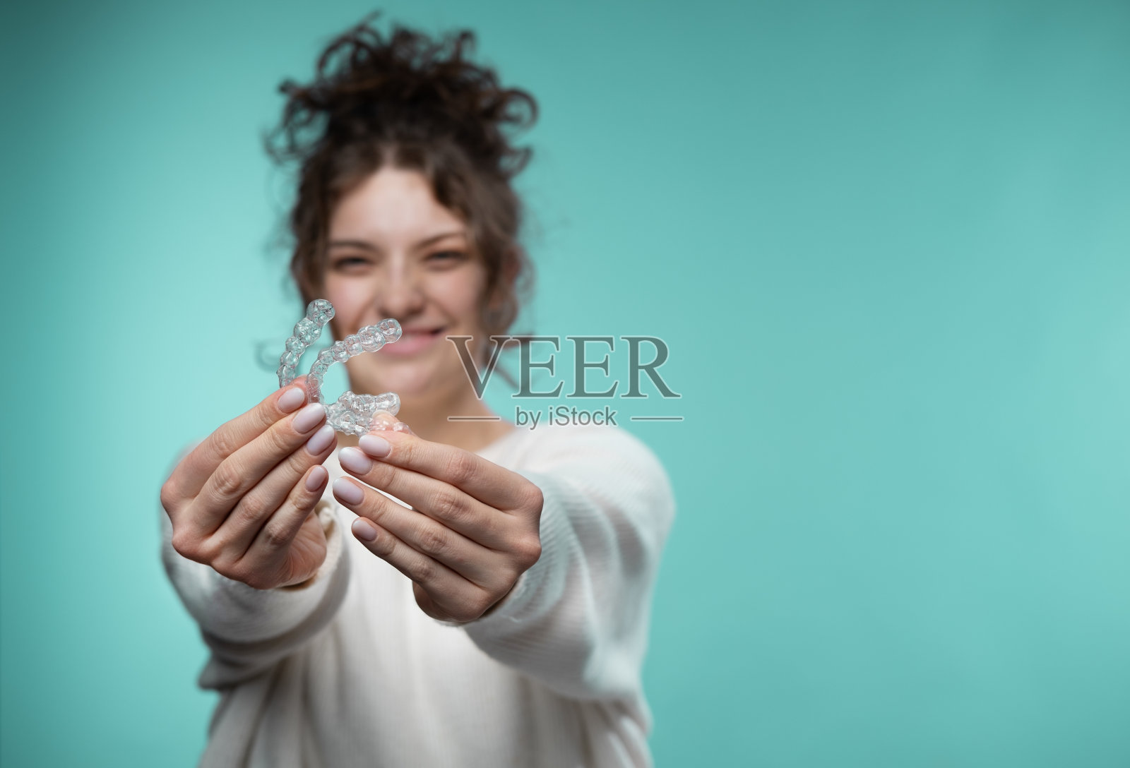 一位女士拿着隐形牙齿矫正器。照片摄影图片