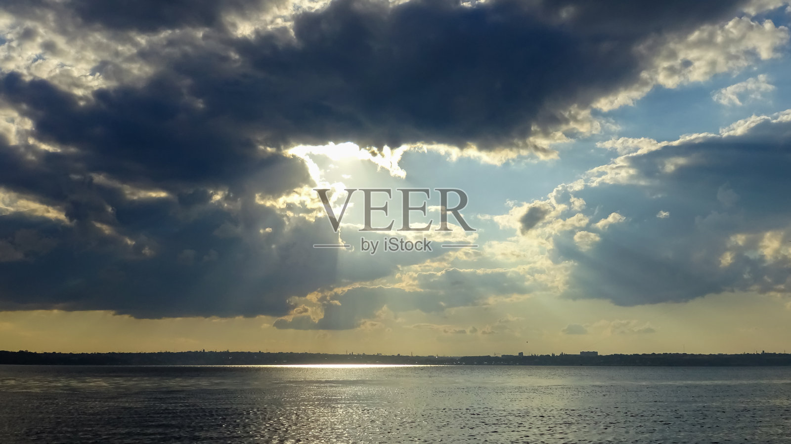 库亚利尼茨基河口上雨前的黑色雷雨云中的太阳光线照片摄影图片