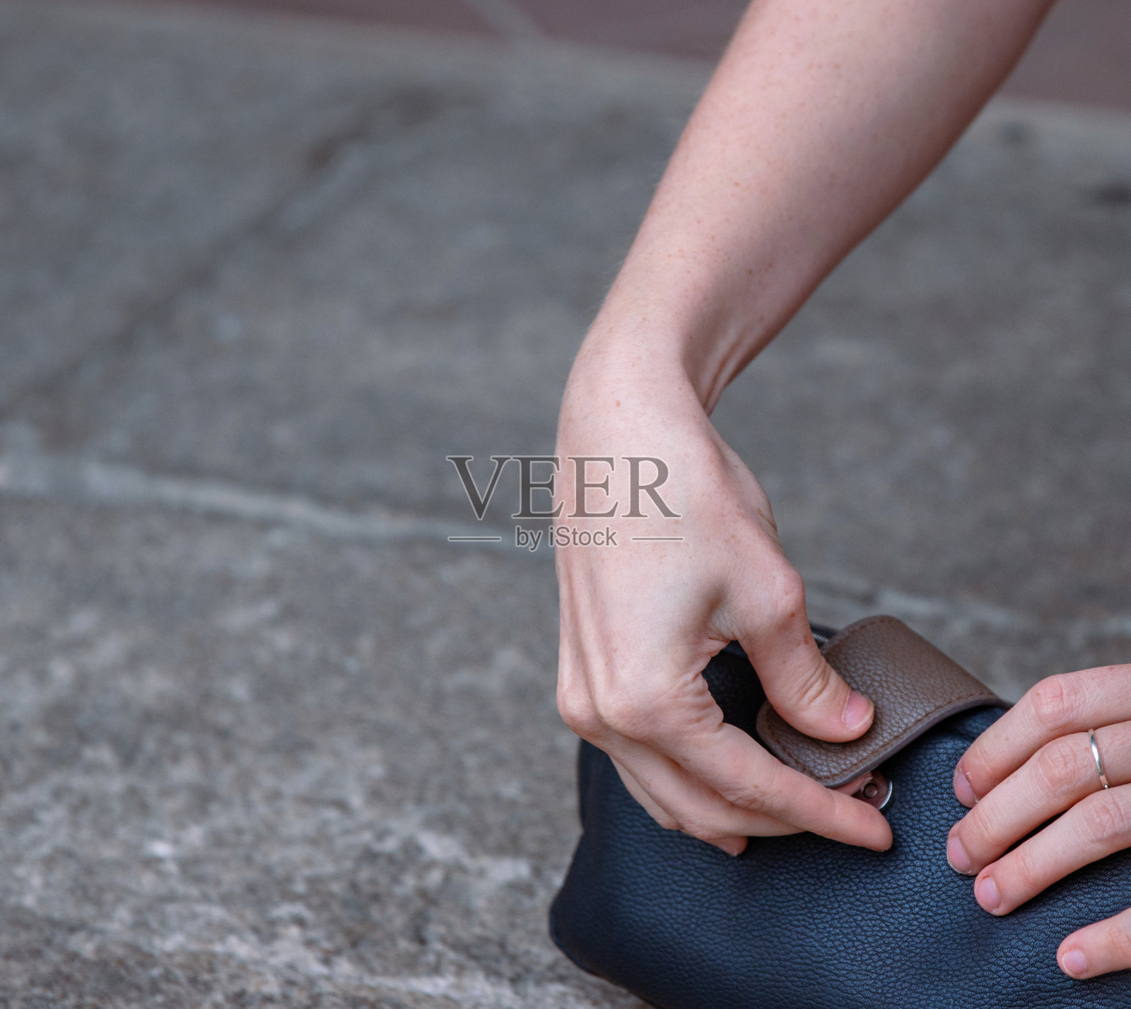 这位年轻芭蕾舞者的腿和手的特写。年轻的女士坐在石头地板上,一边化妆一边打开她的黑色皮革化妆包。后台的时刻。副本的空间。照片摄影图片