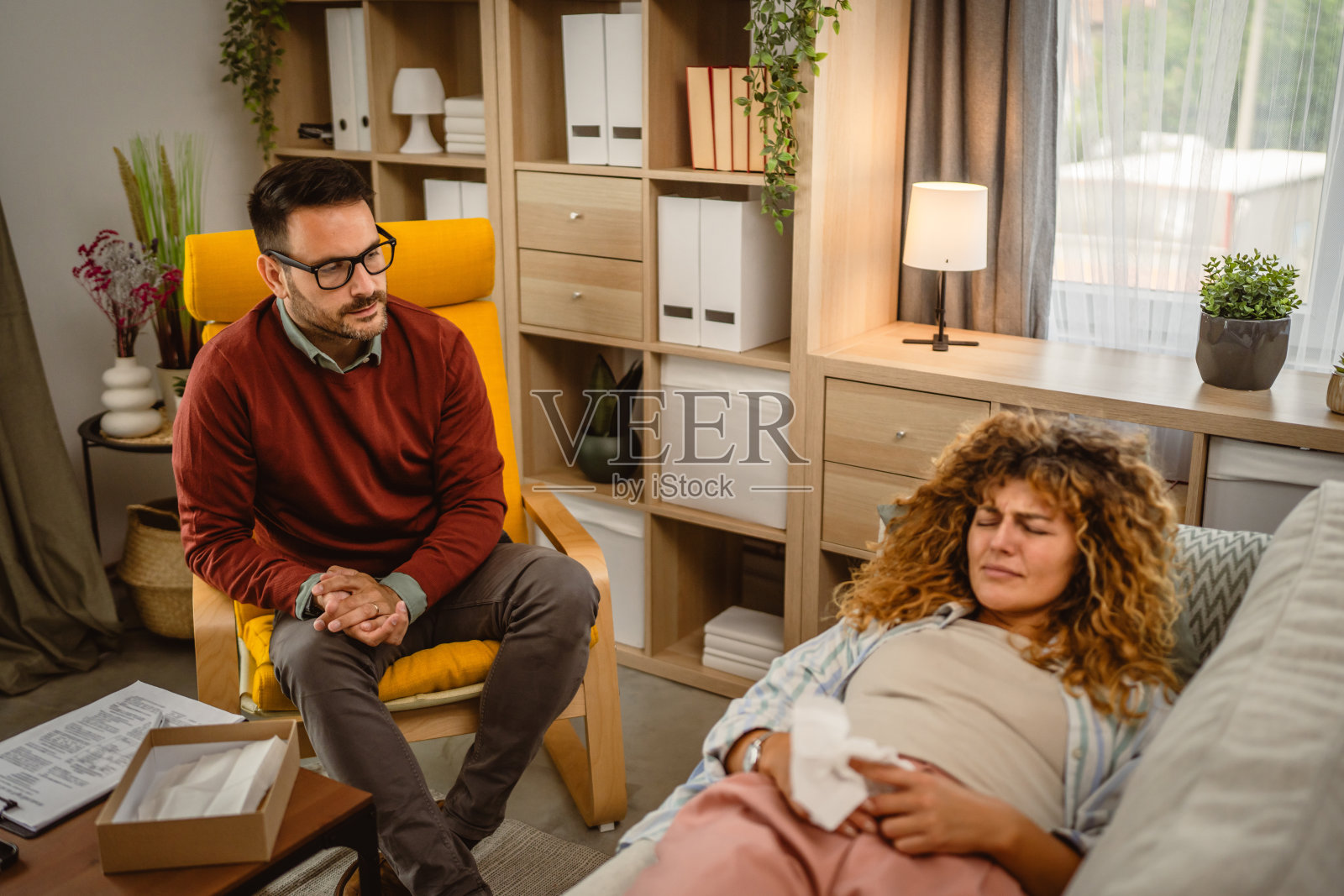 心理治疗师倾听哭泣的女来访者并在剪贴板上写下照片摄影图片