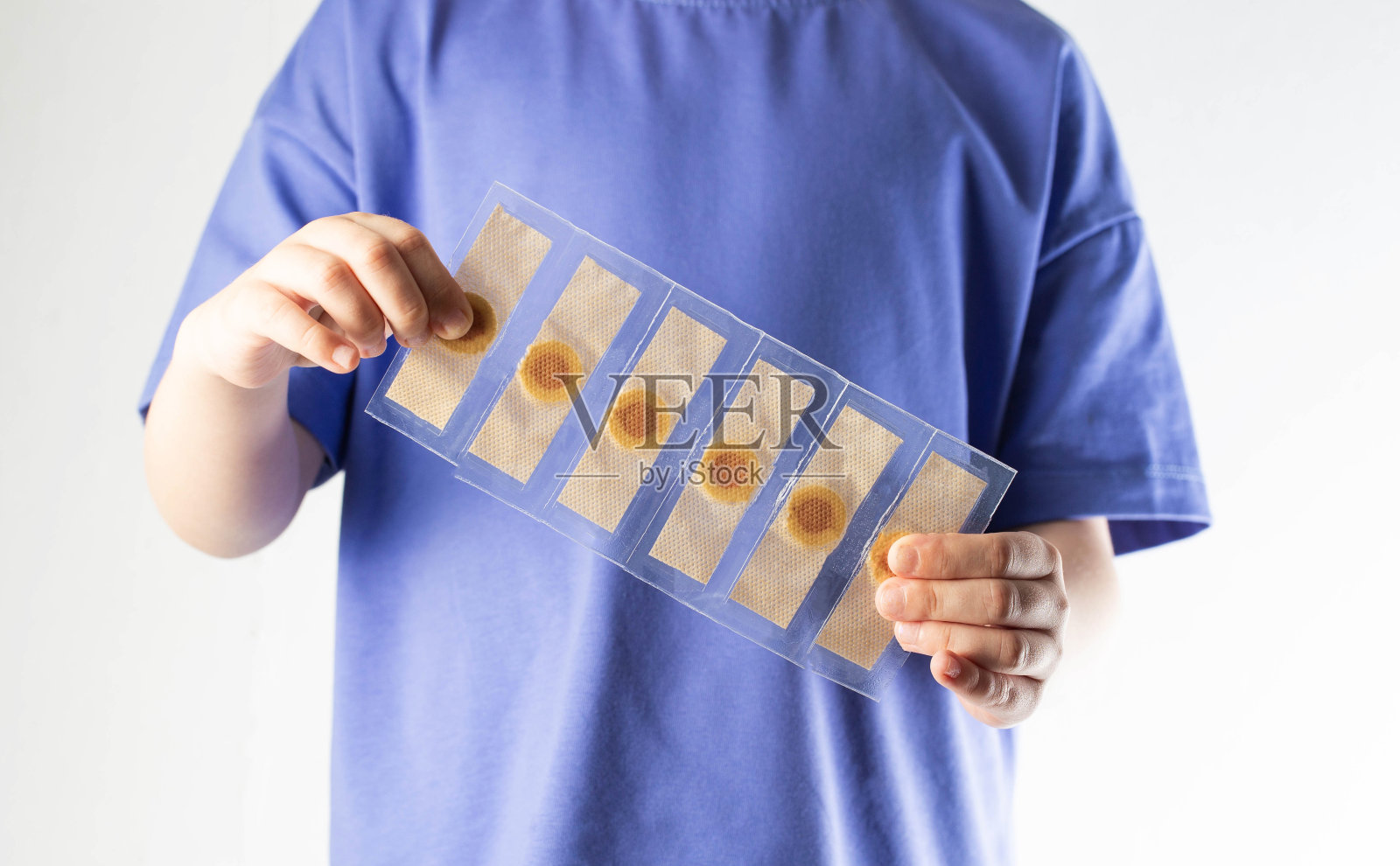 一个孩子手里拿着一个包裹,里面装着治疗核心老茧的膏药(特写)照片摄影图片