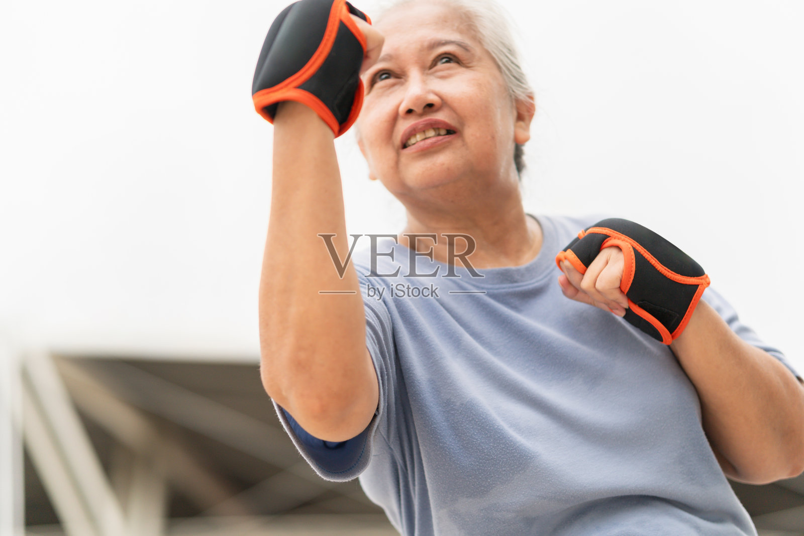 开朗的亚洲资深女运动员一边在户外停车场锻炼,一边打拳击照片摄影图片