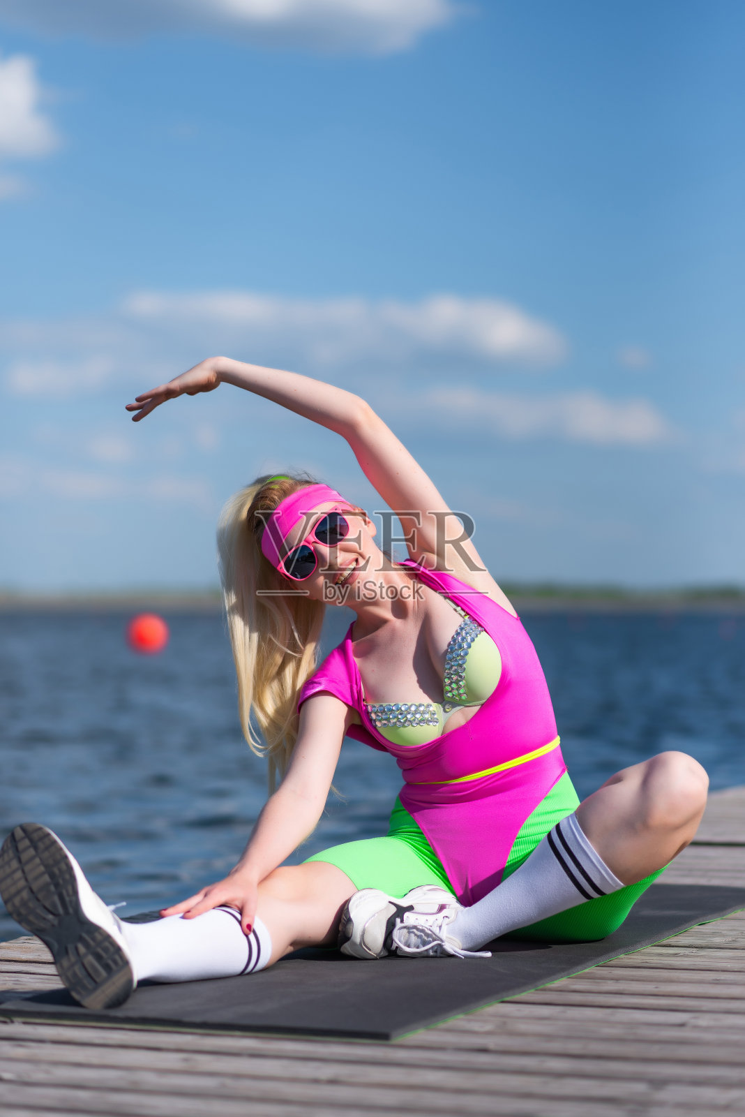 年轻美丽的金发女子穿着运动短裤,粉红色的紧身衣和粉红色的太阳镜在户外做运动。用哑铃做练习。运动,积极的生活方式,运动训练,健康照片摄影图片