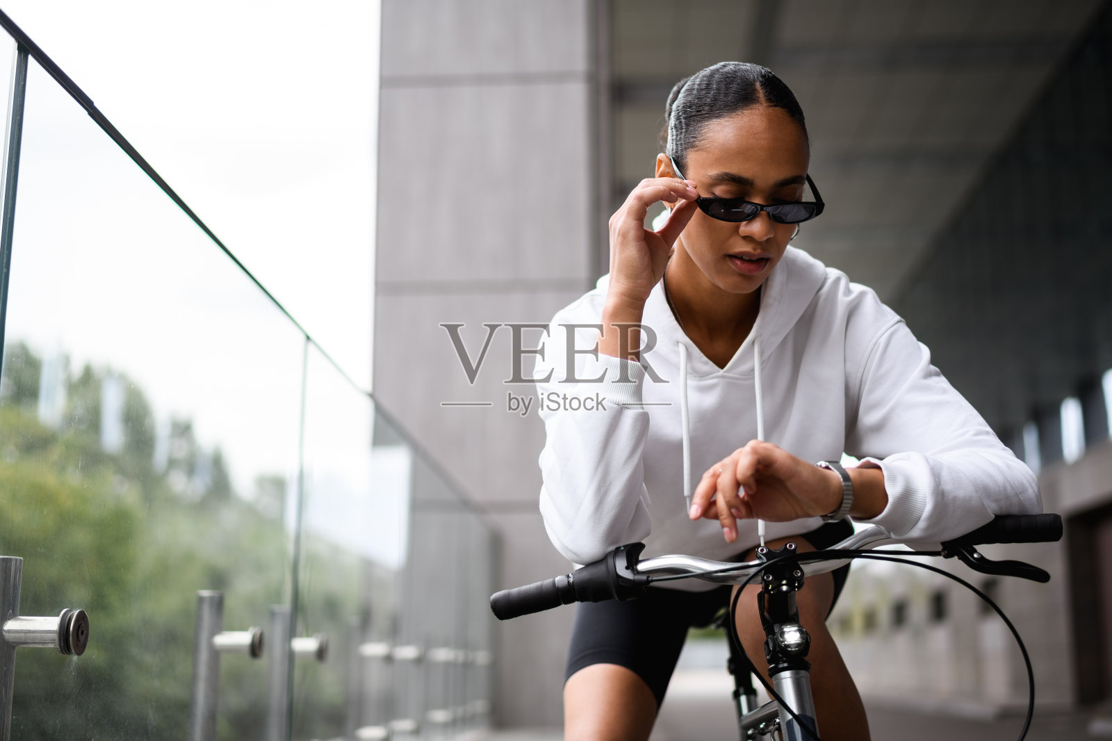 时尚的非裔美国自行车手在街上看手表照片摄影图片