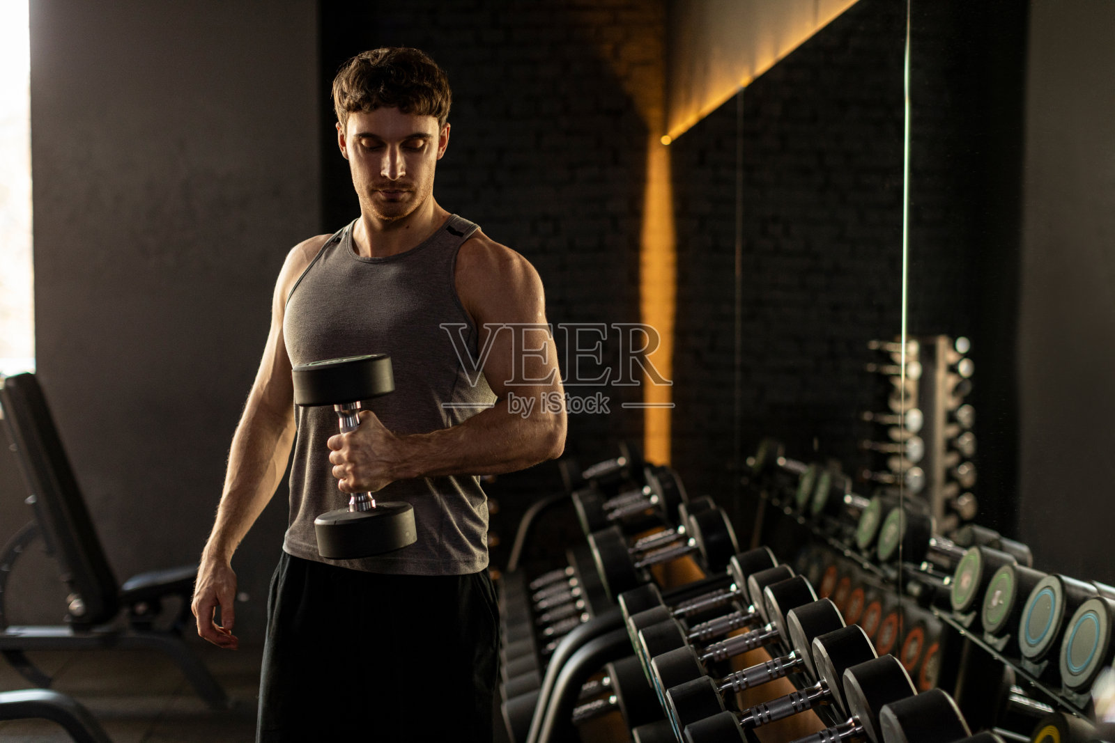 猛男在健身房用哑铃训练,享受健身,在体育俱乐部用重量锻炼照片摄影图片