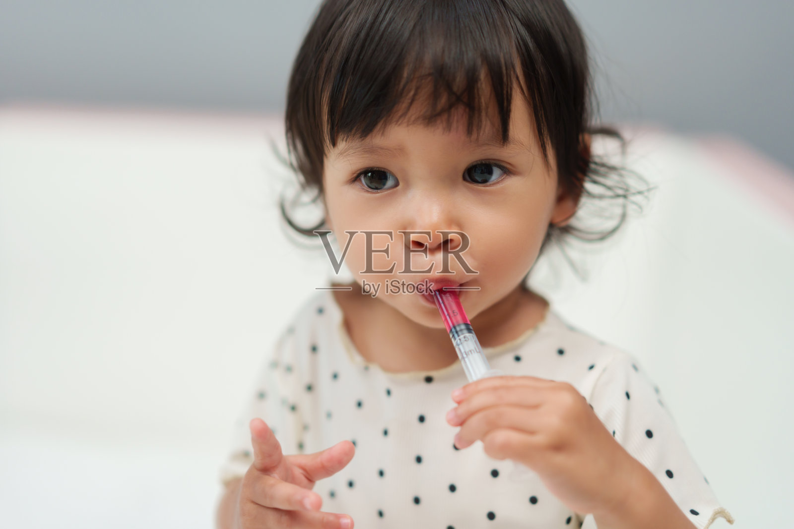 女婴用注射器服用糖浆药。生病的孩子照片摄影图片