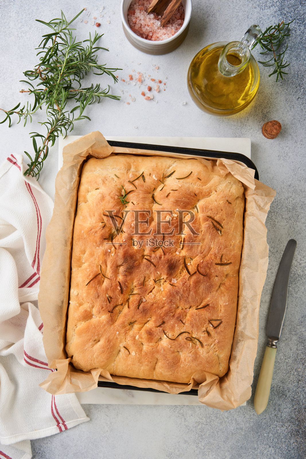 佛卡夏。意大利传统面包和配方烘烤与芳香的调味料和迷迭香在旧混凝土灰色质朴的桌子背景。封面或文章前视图。放文字的地方。照片摄影图片